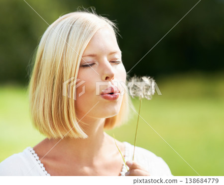 Woman, blowing and dandelion in nature, spring or season for outdoor eco friendly environment. Young female person or blonde with plant, flower or bloom in park for travel or summer in countryside 138684779