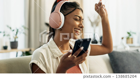 Phone, music and happy woman dance on sofa in home, singing and listening to audio. Smartphone, excited Indian person on headphones and radio, sound or freedom in living room on mobile app technology Phone, music and happy woman dance on sofa in home, singing and listening to audio. Smartphone, excited Indian person on headphones and radio, sound or freedom in living room on mobile app technology 138685204