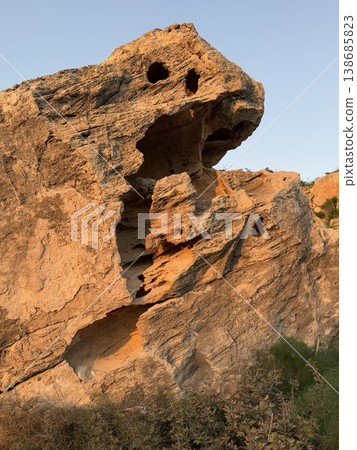 Rock formation at sunset with eroded textures and natural patterns against clear blue sky Rock formation at sunset with eroded textures and natural patterns against clear blue sky 138685823