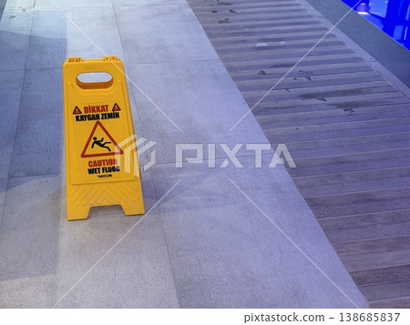 Caution wet floor sign on tiled surface near swimming pool, safety warning, indoor setting background Caution wet floor sign on tiled surface near swimming pool, safety warning, indoor setting background 138685837
