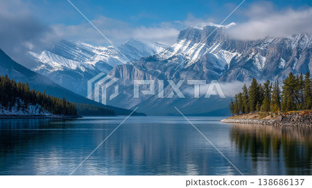 A breathtaking view turquoise lake waters reflecting snow-capped peaks. The scene features dense pine forests and soft morning mist drifting across the rugged Canadian Rockies. 138686137