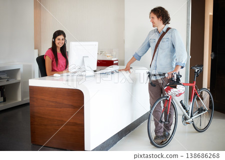Office, desk and man with bike for business, travel and talking about commute to work with receptionist in morning. Businessman, bicycle and conversation with woman in administration or secretary 138686268