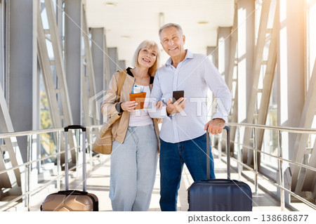 Happy mature couple posing in airport, woman holding passport with boarding pass 138686877