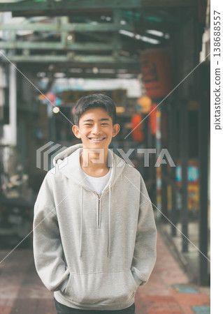 一名身著休閒服的年輕男子在小巷裡笑容燦爛。 一名身著休閒服的年輕男子在小巷裡笑容燦爛。 138688557