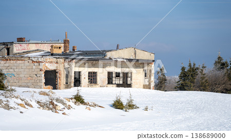 Snow covers the ground around the ruined building in the Jizera Mountains. This site was once a busy mining plant, now silent and left behind in winter's grip. Snow covers the ground around the ruined building in the Jizera Mountains. This site was once a busy mining plant, now silent and left behind in winter's grip. 138689000