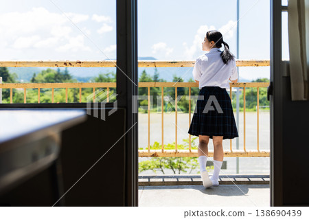 A high school girl gazes at the view from her balcony. A high school girl gazes at the view from her balcony. 138690439