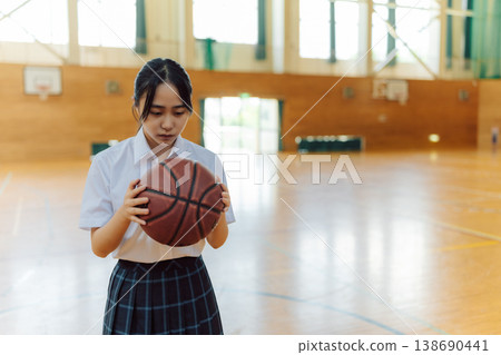 A high school girl stares at a ball in the gymnasium. A high school girl stares at a ball in the gymnasium. 138690441