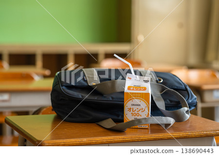 Orange juice and bag placed on the classroom desk 138690443