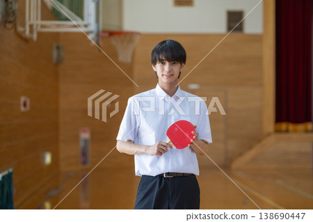 一名高中男生在體育館拿著乒乓球拍。 一名高中男生在體育館拿著乒乓球拍。 138690447