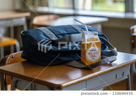 教室桌上放著一袋柳橙汁和一袋袋子。 教室桌上放著一袋柳橙汁和一袋袋子。 138690450