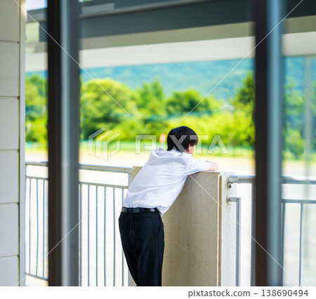 A male high school student looks out from the balcony. A male high school student looks out from the balcony. 138690494