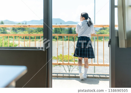 一名高中女生站在教學大樓的陽台上,向窗外眺望。 一名高中女生站在教學大樓的陽台上,向窗外眺望。 138690505