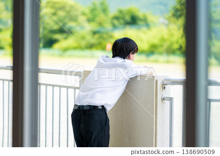 A high school boy looking out the window from the school building's balcony. A high school boy looking out the window from the school building's balcony. 138690509