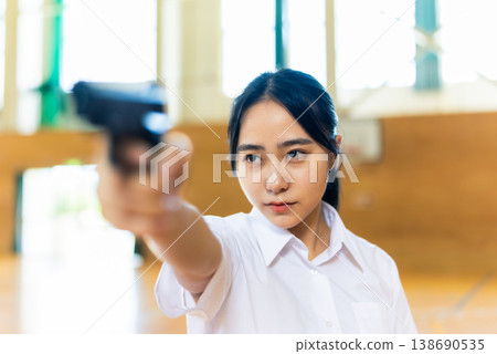 A high school girl looks to the side while holding a gun. A high school girl looks to the side while holding a gun. 138690535