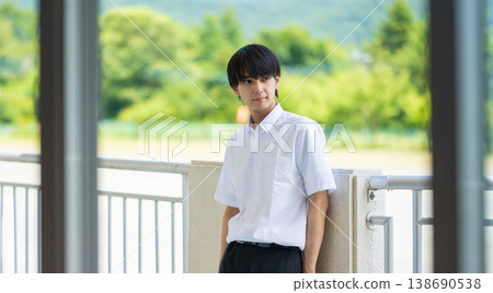 一名高中男生站在戶外露臺上,凝視著遠方。 一名高中男生站在戶外露臺上,凝視著遠方。 138690538