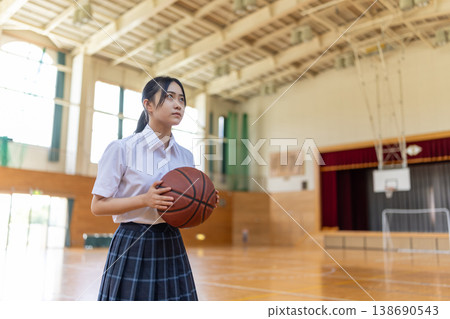 一名身穿校服的女學生抱著一個籃球。 138690543