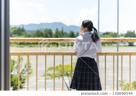 A high school girl looking out the window from the school building's balcony. A high school girl looking out the window from the school building's balcony. 138690544