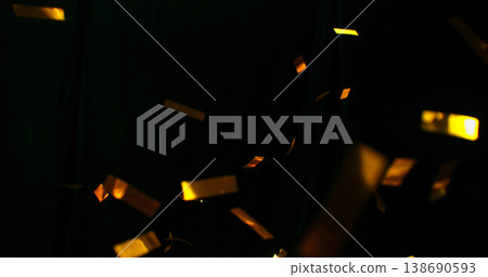 Flying golden confetti on black background. Shiny particles suspended in the air with dramatic lighting, creating a festive, luxury and celebratory atmosphere. Flying golden confetti on black background. Shiny particles suspended in the air with dramatic lighting, creating a festive, luxury and celebratory atmosphere. 138690593