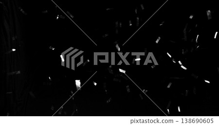 Flying silver confetti on black background. Shiny metallic particles suspended in the air with dramatic lighting, creating a festive, elegant and celebratory atmosphere. 138690605