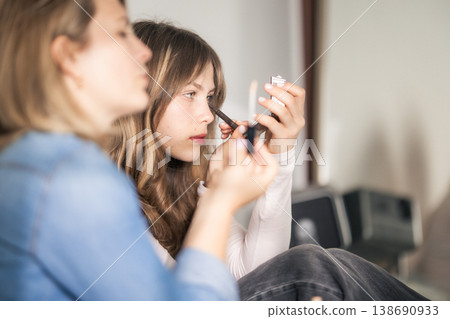 Young woman applying makeup using compact mirror Young woman applying makeup using compact mirror 138690933