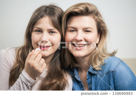 Mother and daughter applying lip gloss, sharing beauty moment Mother and daughter applying lip gloss, sharing beauty moment 138690983