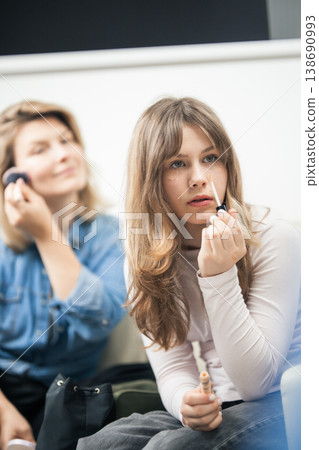 Young girl applying make-up with mother in background 138690993