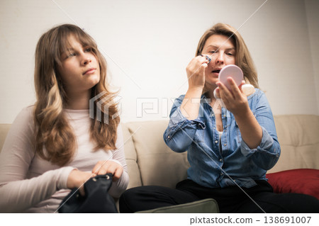 Mother applying makeup while daughter looks on Mother applying makeup while daughter looks on 138691007
