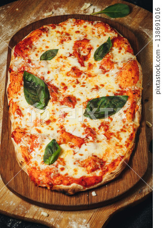 Traditional Italian pinsa romana margherita with melted mozzarella cheese fresh basil and tomato sauce on a rustic wooden board with flour. Traditional Italian pinsa romana margherita with melted mozzarella cheese fresh basil and tomato sauce on a rustic wooden board with flour. 138691016
