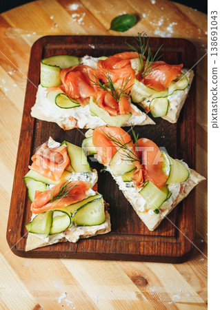 Smoked salmon bruschettas with fresh cucumber ribbons, cream cheese and dill on a rustic wooden board. Smoked salmon bruschettas with fresh cucumber ribbons, cream cheese and dill on a rustic wooden board. 138691043