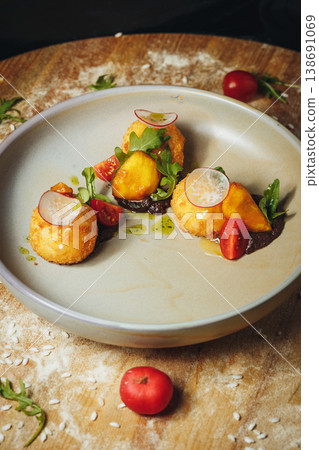 Gourmet fried arancini balls served with dark savory sauce fresh cherry tomatoes and radish slices on a ceramic plate. Gourmet fried arancini balls served with dark savory sauce fresh cherry tomatoes and radish slices on a ceramic plate. 138691069