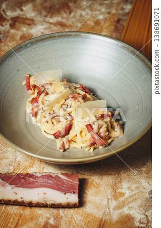 Authentic Pasta Carbonara with crispy guanciale creamy egg sauce and parmesan shavings served in a ceramic bowl on a rustic background. Authentic Pasta Carbonara with crispy guanciale creamy egg sauce and parmesan shavings served in a ceramic bowl on a rustic background. 138691071