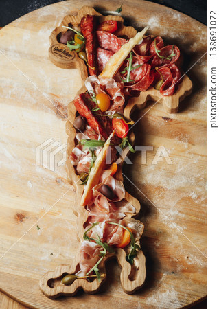 Authentic Italian antipasto platter with prosciutto salami olives and tomatoes served on a wooden board shaped like the map of Italy. Authentic Italian antipasto platter with prosciutto salami olives and tomatoes served on a wooden board shaped like the map of Italy. 138691072