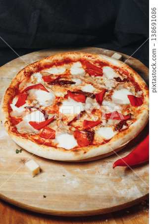 Traditional Italian pizza topped with fresh tomato sauce melted mozzarella savory ham and roasted red peppers on a rustic wooden board. 138691086