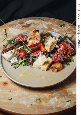 Gourmet Italian antipasto platter with prosciutto salami gorgonzola cheese parmesan walnuts and fresh cherry tomatoes on a ceramic plate. 138691095