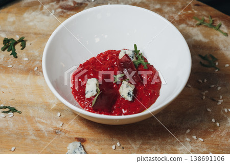 Gourmet beetroot risotto with a vibrant red color topped with creamy blue cheese and fresh microgreens in a white ceramic bowl. Gourmet beetroot risotto with a vibrant red color topped with creamy blue cheese and fresh microgreens in a white ceramic bowl. 138691106