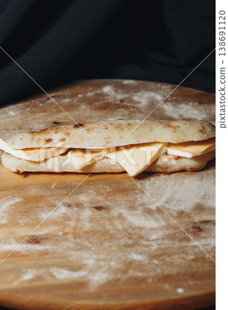 Traditional Italian saltimbocca sandwich made from pizza dough filled with sliced brie cheese on a rustic floured wooden board. Traditional Italian saltimbocca sandwich made from pizza dough filled with sliced brie cheese on a rustic floured wooden board. 138691120
