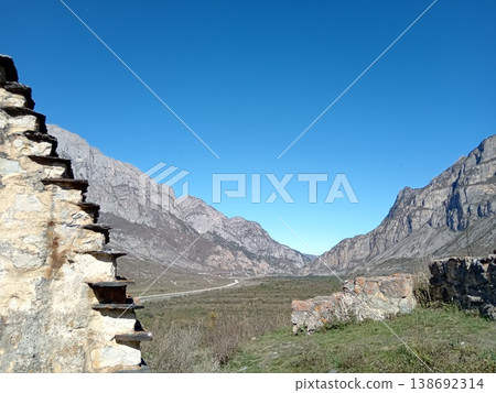 City of the Dead, Dargavs, North Ossetia, Russia. Overhead view of the ancient cemetery with crypts stretching across the green terrain towards the mountains City of the Dead, Dargavs, North Ossetia, Russia. Overhead view of the ancient cemetery with crypts stretching across the green terrain towards the mountains 138692314