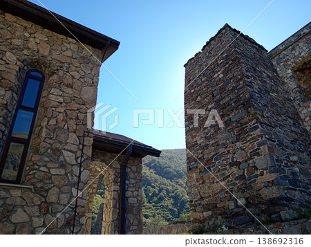 North Ossetia's Stone Alan Monastery on a bright summer day, Russia. Ancient monastic ruins and preserved structures in a high-altitude mountain landscape North Ossetia's Stone Alan Monastery on a bright summer day, Russia. Ancient monastic ruins and preserved structures in a high-altitude mountain landscape 138692316