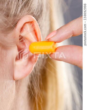 Woman putting earplugs Woman putting earplugs 138692998