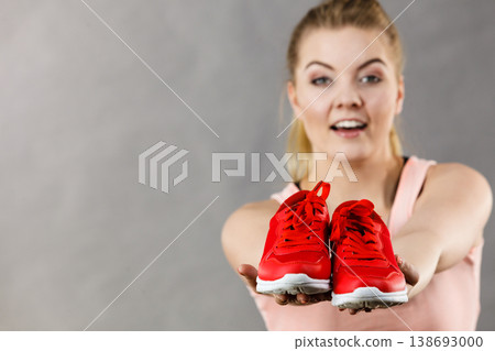 Happy woman presenting sportswear trainers shoes Happy woman presenting sportswear trainers shoes 138693000