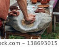 Human hand rotating an ancient stone grinding machine for smashing grains. Handmade manual equipment grind mill 138693015