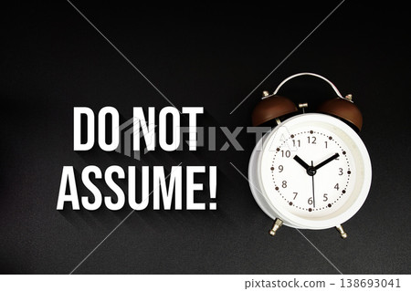 Do Not Assume! text with alarm clock on black background Do Not Assume! text with alarm clock on black background 138693041