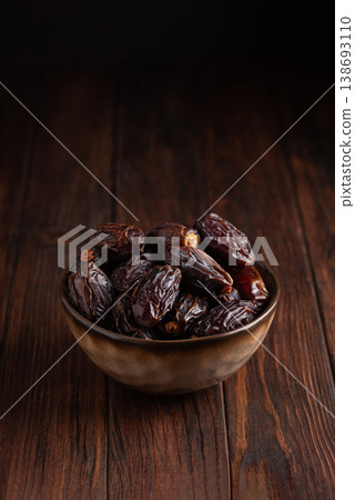 Medjoul Dates in Rustic Ceramic Bowl on Dark Wooden Background Medjoul Dates in Rustic Ceramic Bowl on Dark Wooden Background 138693110
