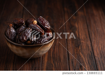 Medjoul Dates in Rustic Ceramic Bowl on Dark Wooden Background Medjoul Dates in Rustic Ceramic Bowl on Dark Wooden Background 138693111
