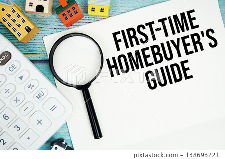 Notepad with "First-Time Homebuyer's Guide" with Calculator, magnifying glass and house model on wooden background 138693221