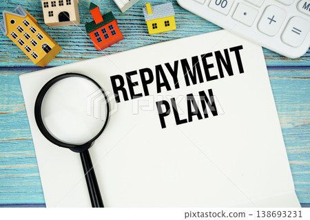 Notepad with "Repayment Plan" with Calculator, magnifying glass and house model on wooden background Notepad with "Repayment Plan" with Calculator, magnifying glass and house model on wooden background 138693231