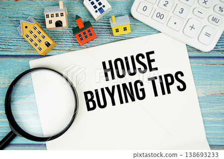 Notepad with "House Buying Tips" with Calculator, magnifying glass and house model on wooden background Notepad with "House Buying Tips" with Calculator, magnifying glass and house model on wooden background 138693233