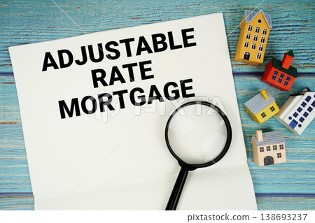 Notepad with "ARM Adjustable Rate Mortgage" with magnifying glass and house model on wooden background Notepad with "ARM Adjustable Rate Mortgage" with magnifying glass and house model on wooden background 138693237