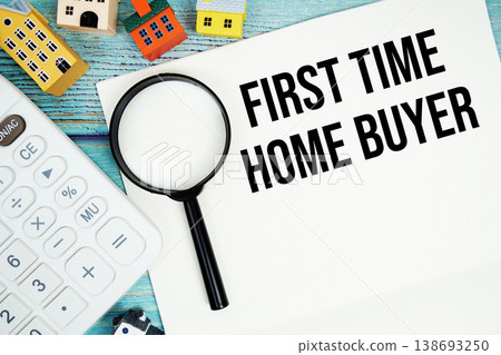 Notepad with "First Time Home Buyer" with Calculator, magnifying glass and house model on wooden background 138693250