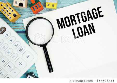 Notepad with "Mortgage Loan" with Calculator, magnifying glass and house model on wooden background Notepad with "Mortgage Loan" with Calculator, magnifying glass and house model on wooden background 138693253